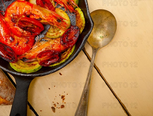 Roasted shrimps on cast iron skillet with zucchini and tomatoes