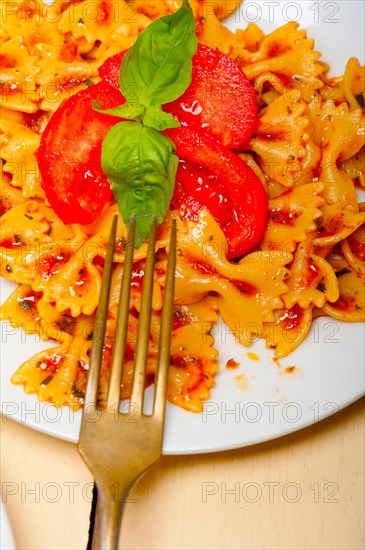 Italian pasta farfalle butterfly bow-tie with tomato basil sauce over white rustic wood table