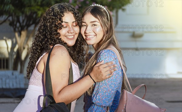 Two female friends hugging in front outdoors