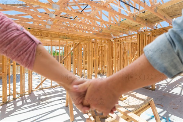 A couple hold his hands and looking at their new house under construction