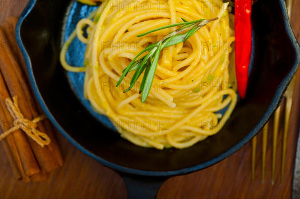 Italian spaghetti pasta with zucchini sauce on iron skillet over wood board