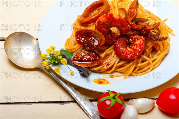 Italian seafood spaghetti pasta on red tomato sauce over white rustic wood table