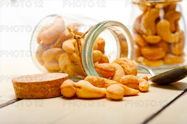 Cashew nuts on a glass jar over white rustic wood table