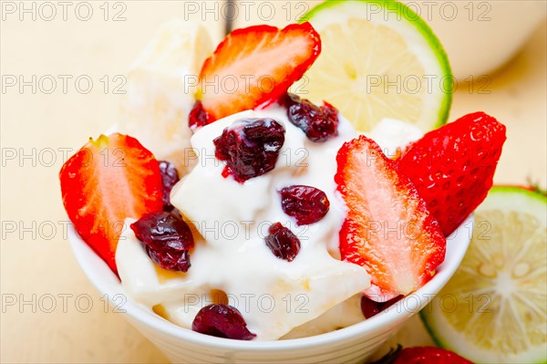 Fruit and yogurt salad healthy breakfast over white wood table