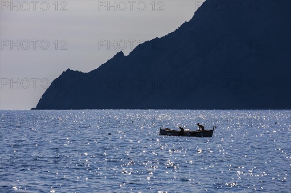 A fishing boat in the glittering sea of the evening sun in front of Vernazza