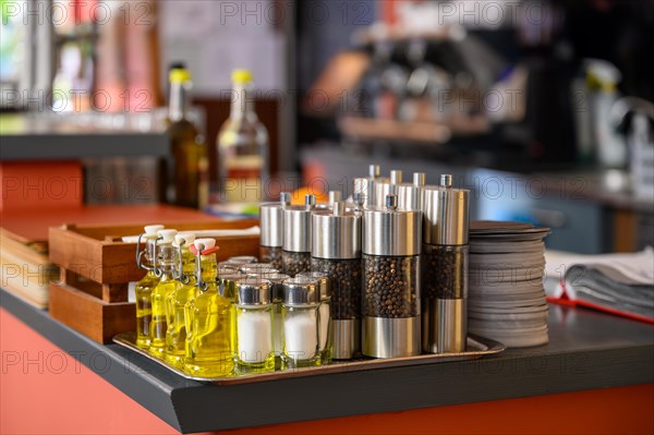 Salt and pepper shakers and small bottles of olive oil are placed on the counter of a restaurant