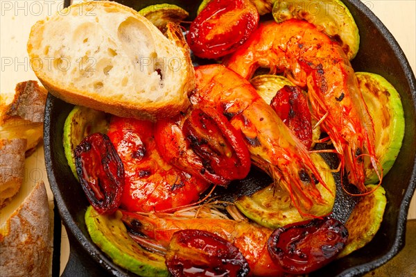 Roasted shrimps on cast iron skillet with zucchini and tomatoes