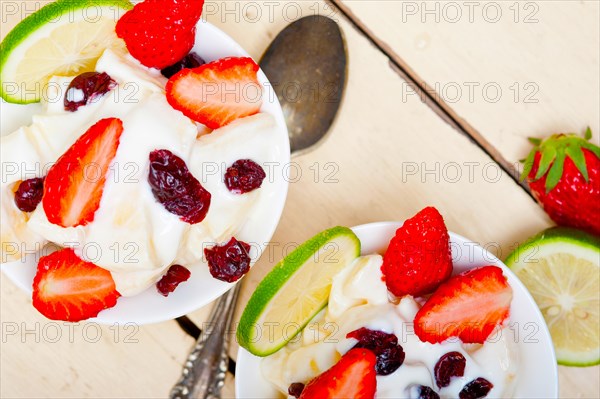 Fruit and yogurt salad healthy breakfast over white wood table