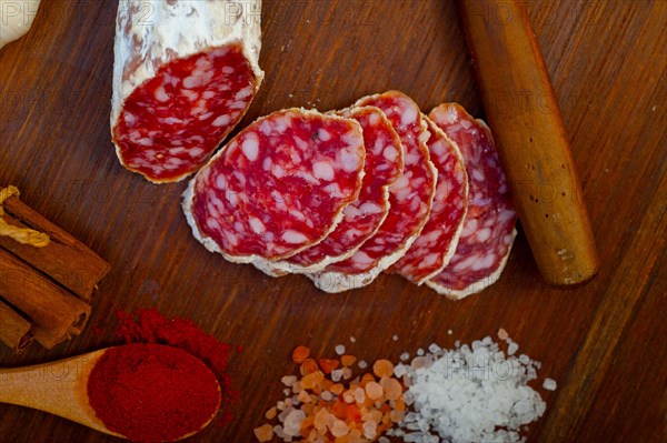 Traditional Italian salame cured sausage sliced on a wood board