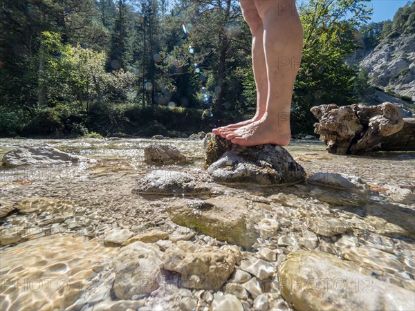 Feet of a woman in a clear small mountain river in the Oetschergraeben in Lower Austria