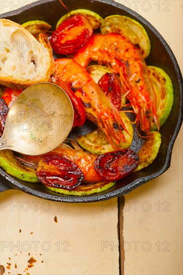 Roasted shrimps on cast iron skillet with zucchini and tomatoes