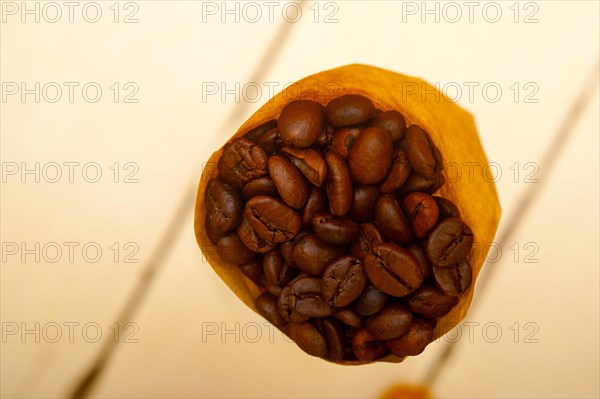 Espresso coffee beans on a paper cone cornucopia over white background