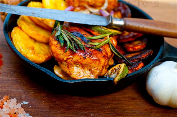 Roasted grilled BBQ chicken breast with herbs and spices rustic style on iron skillet