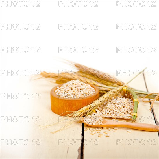 Organic wheat grains over rustic wood table macro closeup