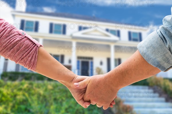 A couple hold his hands approaching the front door of a new house