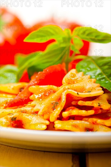 Italian pasta farfalle butterfly bow-tie with tomato basil sauce over white rustic wood table