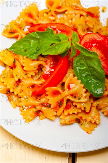 Italian pasta farfalle butterfly bow-tie with tomato basil sauce over white rustic wood table