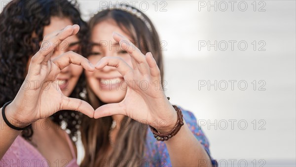 Close up of two girls forming heart with hands