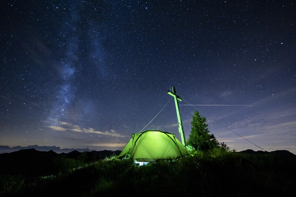 Green tent with summit cross under a starry sky on Portlakopf