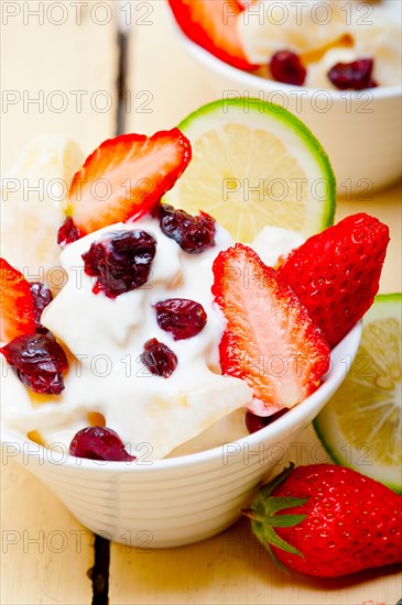 Fruit and yogurt salad healthy breakfast over white wood table