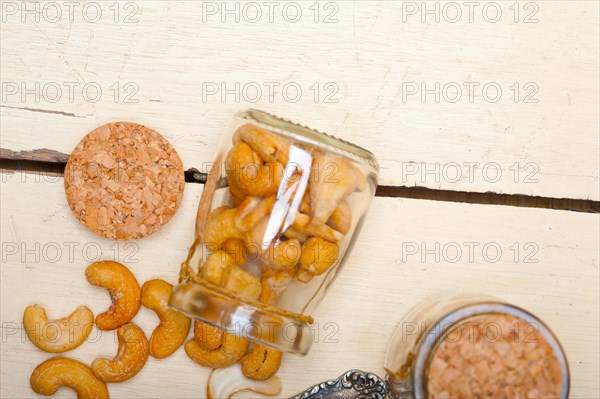 Cashew nuts on a glass jar over white rustic wood table