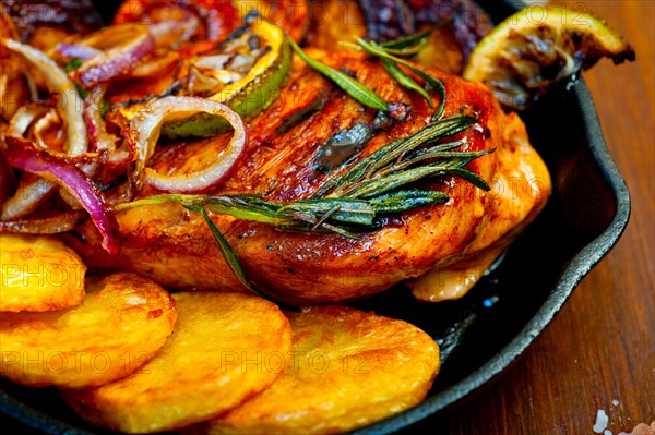 Roasted grilled BBQ chicken breast with herbs and spices rustic style on iron skillet