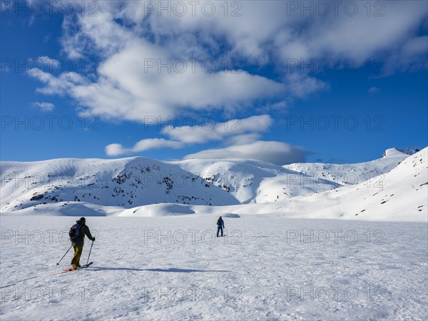 Two ski tourers crossing a frozen lake in the winter mountains