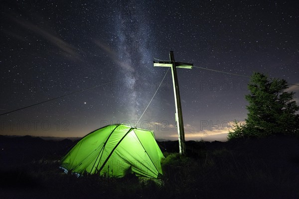 Green tent with summit cross under a starry sky on Portlakopf