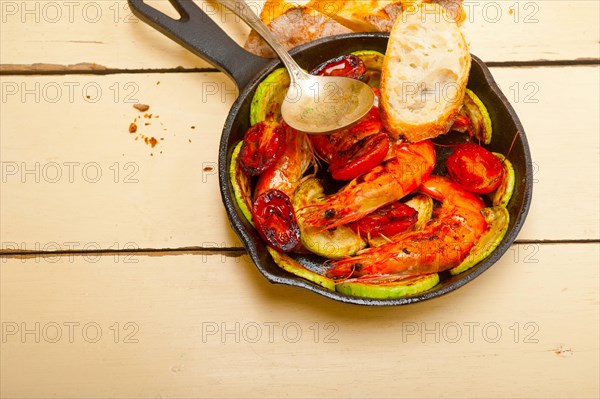 Roasted shrimps on cast iron skillet with zucchini and tomatoes