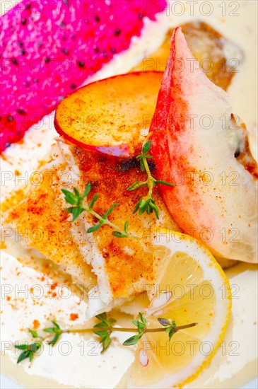 Sea bream orata fillet butter pan fried with fresh peach prune and dragonfruit slices thyme on top