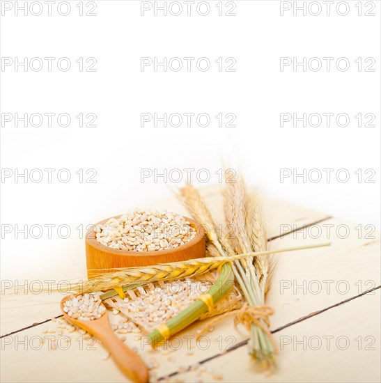 Organic barley grains over rustic wood table macro closeup