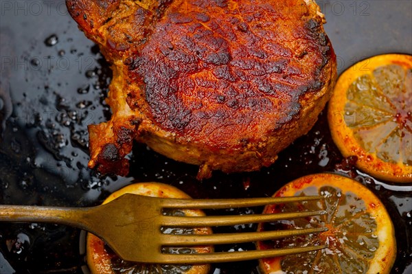 Pork chop seared on iron skillet with lemon and spices seasoning