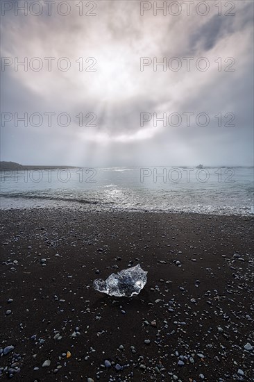 Ice crystal and pebbles on the black lava beach