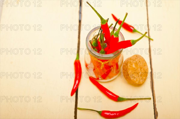 Red chili peppers on a glass jar over white wood rustic table