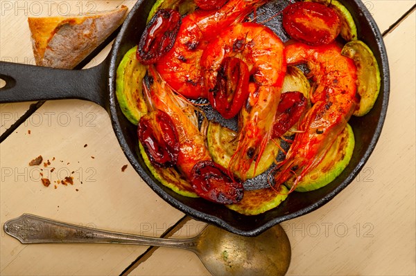 Roasted shrimps on cast iron skillet with zucchini and tomatoes