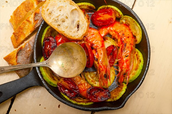 Roasted shrimps on cast iron skillet with zucchini and tomatoes