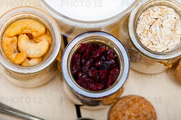 Healthy breakfast ingredients milk oat cashew nuts dried cramberry craisinns