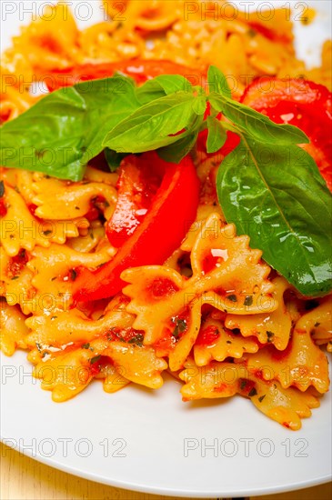 Italian pasta farfalle butterfly bow-tie with tomato basil sauce over white rustic wood table