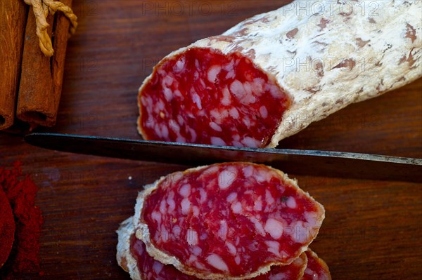 Traditional Italian salame cured sausage sliced on a wood board