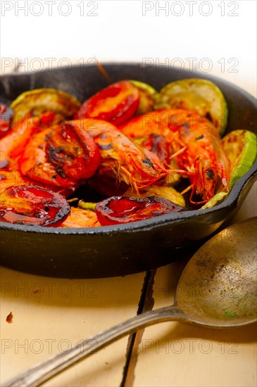 Roasted shrimps on cast iron skillet with zucchini and tomatoes