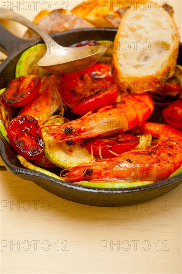 Roasted shrimps on cast iron skillet with zucchini and tomatoes