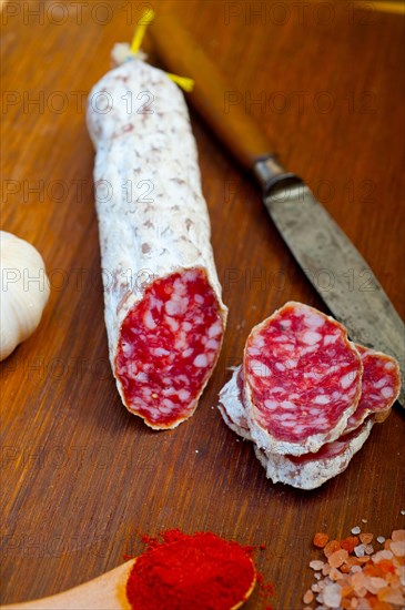 Traditional Italian salame cured sausage sliced on a wood board