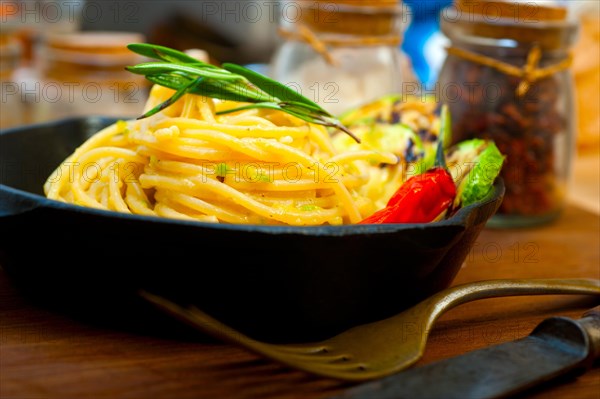 Italian spaghetti pasta with zucchini sauce on iron skillet over wood board