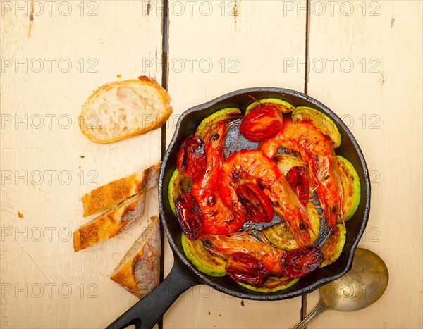 Roasted shrimps on cast iron skillet with zucchini and tomatoes