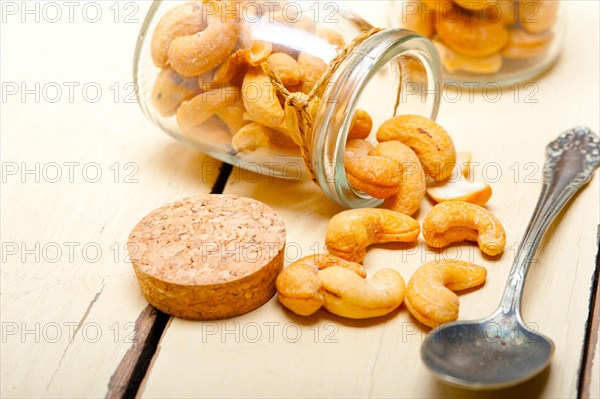 Cashew nuts on a glass jar over white rustic wood table