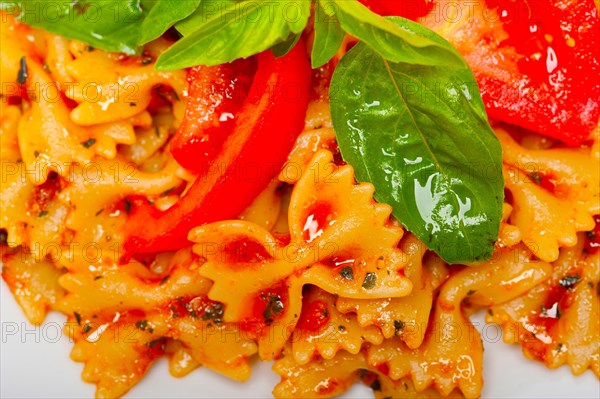 Italian pasta farfalle butterfly bow-tie with tomato basil sauce over white rustic wood table