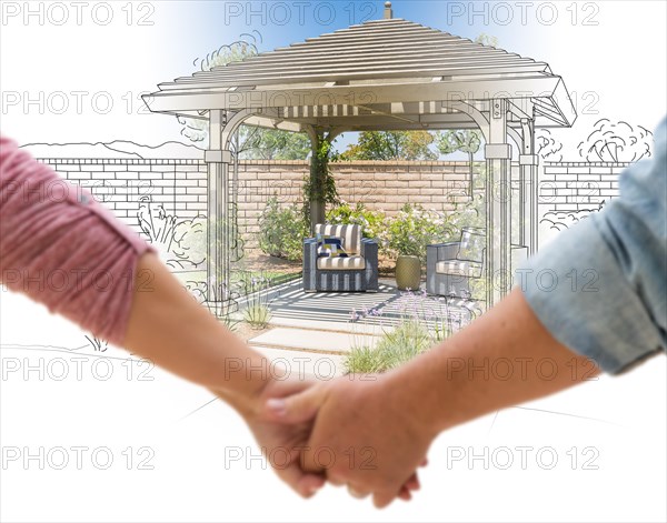 A couple hold his hands looking at design and photo of new yard pergola