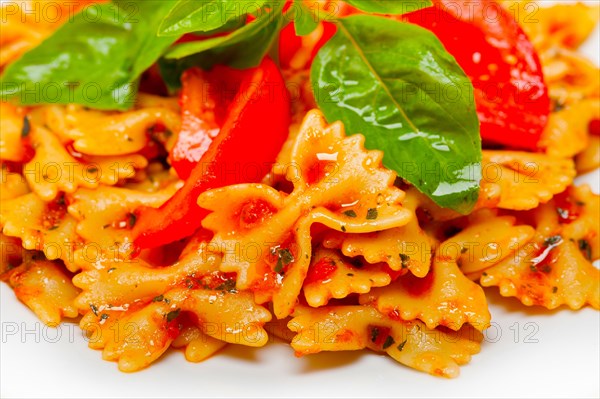 Italian pasta farfalle butterfly bow-tie with tomato basil sauce over white rustic wood table