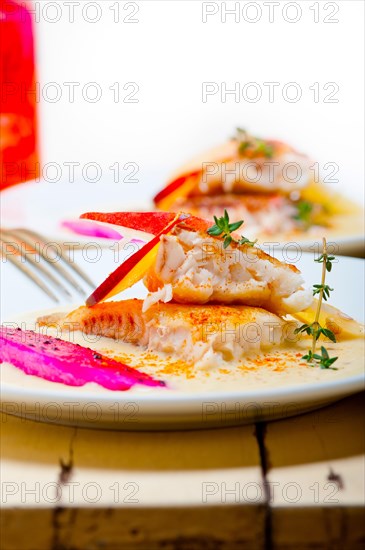 Sea bream orata fillet butter pan fried with fresh peach prune and dragonfruit slices thyme on top