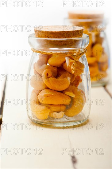 Cashew nuts on a glass jar over white rustic wood table